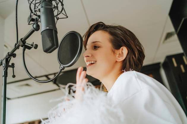 Happy young singer recording podcast through microphone in studio model released, Symbolfoto property released, MDOF00353
