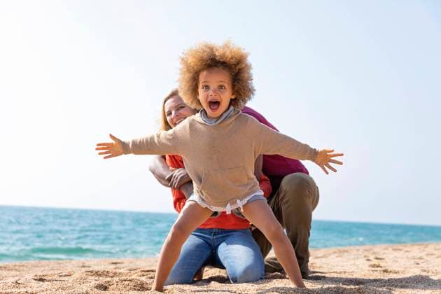 Screaming girl standing with arms outstretched in front of mother and father at beach model released, Symbolfoto, MEGF00297