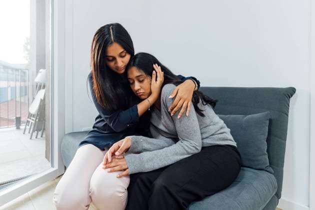 IMAGO Creative, Lifestyle, Leben in einer Wohngemeinschaft, WG Young woman consoling sister on sofa in living room model released, Symbolfoto property released, MEUF08657
