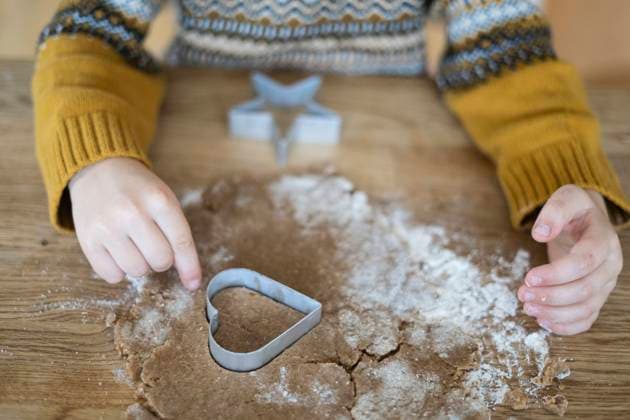 Hands of boy cutting out cookie with heart shaped cutter on table model released, Symbolfoto, NJAF00080