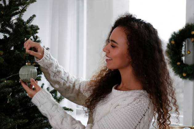 Smiling woman decorating Christmas tree with bauble at home model released, Symbolfoto property released, SYEF00151