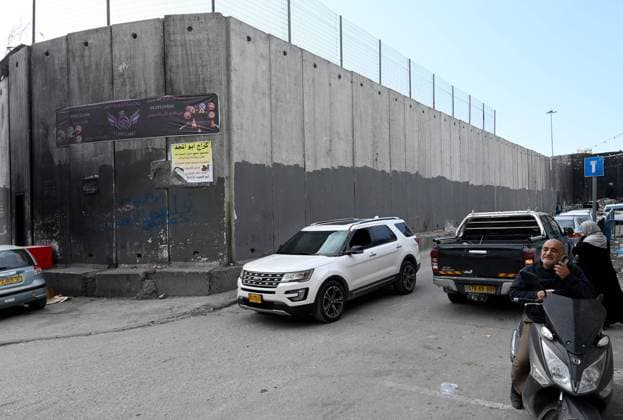 Palestinians drive beside the Israeli separation wall that surrounds the Shuafat Refugee Camp in Jerusalem on Tuesday, January 3, 2023.  JER2023010311 DEBBIExHILL