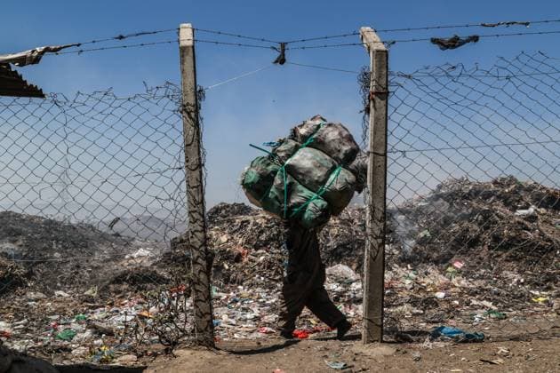 January 13, 2023, Nakuru, Kenya: A waste picker carries bags with waste for recycling next to burning garbage at the Nakuru main dumping yard. Since waste is rarely segregated and is heavily mixed with all sorts of trash, burning it can produce potentially toxic fumes that can be a public health problem and can also contribute to climate change. Communities working and living near dumping sites where garbage is openly burned are at risk of contracting respiratory diseases and cancers. Women exposed to those fumes may suffer from reproductive health problems. Nakuru Kenya - ZUMAs197 20230113_zaa_s197_386 Copyright: xJamesxWakibiax