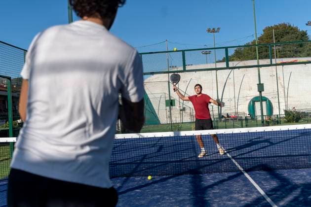 Young man with friend playing paddle tennis at sports court on sunny day model released, Symbolfoto property released, FMOF01606