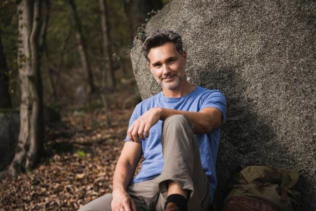 Smiling mature man sitting by rock model released, Symbolfoto, UUF27846