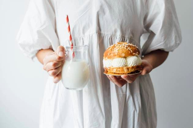 Woman with milk jar and small cake in front of white wall model released, Symbolfoto, EGHF00700