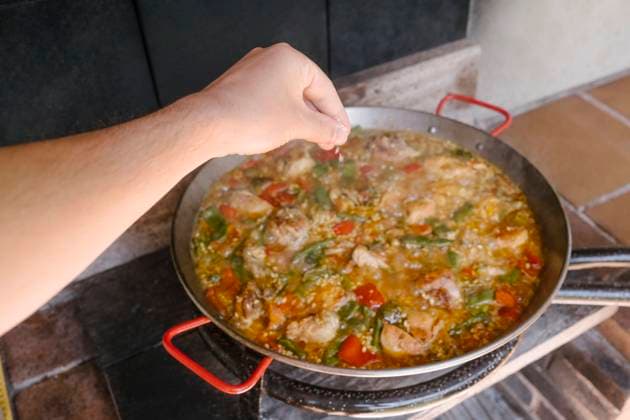 Hand of man adding preparing paella at outdoor kitchen model released, Symbolfoto, MMPF00602