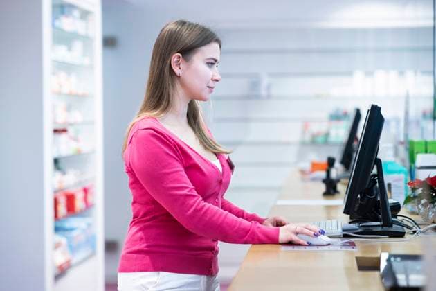 Pharmacist working on desktop PC at counter in pharmacy model released, Symbolfoto property released, NJAF00173