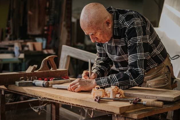 Focused elderly craftsman in casual wear using ruler and pencil while measuring wooden detail in professional joinery, Model released DavidGari_ID11724_351200_028 Copyright: xDavidxGarix MR