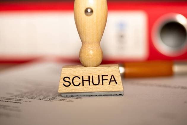 Symbolbild Schufa(Auskunft): Stempel auf einem Schreibtisch mit Dokumenten und Ordnern *** Symbol image Schufa information stamp on a desk with documents and folders Copyright: xx