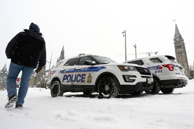 January 29, 2023, Ottawa, ON, CAN: A person passes police officers in their vehicles on Wellington Street in front of Parliament Hill as demonstrators mark the one year anniversary of the Freedom Convoy on Parliament Hill in Ottawa, on Sunday, Jan. 29, 2023. Ottawa CAN  - ZUMAc35_ 20230129_zaf_c35_008 Copyright: xJustinxTangx