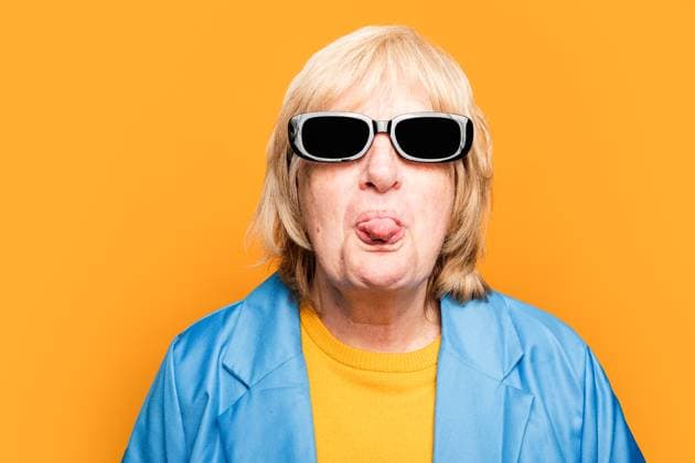 Portrait of elderly female in trendy sunglasses and bright clothes looking at camera while showing tongue against orange background, Model released HodeiUnzueta_ID12634_384192_007 Copyright: xHodeixUnzuetax MR