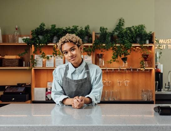 Creative Highlights Symbolbilder Barista in an apron with short curly hair leaning on a counter. Coffeeshop owner looking at camera. Barista in an apron with short curly hair leaning on a counter. Coffeeshop owner looking at camera. Copyright: xArtemxVarnitsinxArtemxVarnitsinx