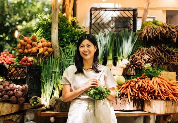 Creative Highlights Symbolbilder Cheerful Asian woman with a shopping bag standing at a farmers market. Young female standing at a stall in an outdoor market and looking at camera. Cheerful Asian woman with a shopping bag standing at a farmers market. Young female standing at a stall in an outdoor market and looking at camera. Copyright: xArtemxVarnitsinxArtemxVarnitsinx