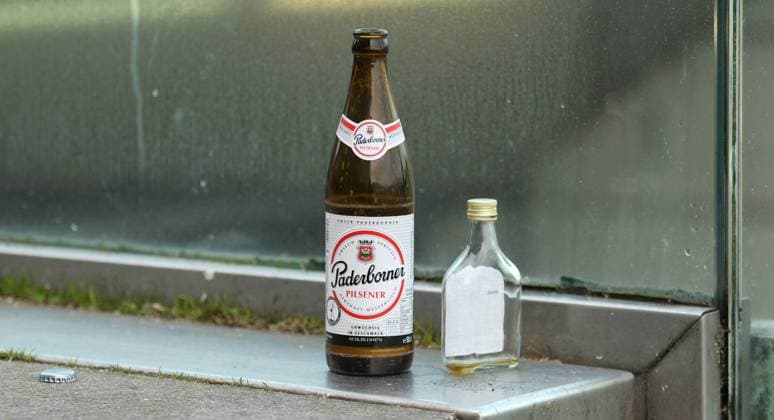Eine leere Bierflasche der Marke Paderborner sowie leere Spirituosenflasche stehen auf einer Treppe in der Hamburger Altstadt. Symbolbild Alkoholsucht. Altstadt Hamburg *** An empty beer bottle of the brand Paderborner as well as empty liquor bottle stand on a staircase in the Hamburg old town symbol picture alcohol addiction old town Hamburg