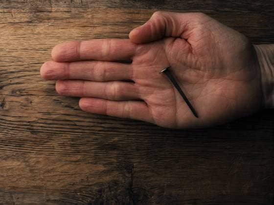 Hand with an old rusty nail symbolizes the crucifixion of Jesus. Easter concept with text free space