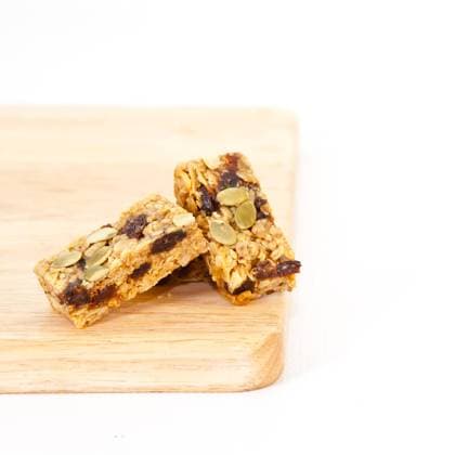 Pumpkin seed and raisin flapjack on a wooden chopping board, white background Copyright: xTomxGowanlockx xDesignxPicsx , 31937352  Copyright: TomxGowanlockx xDesignxPics 31937352