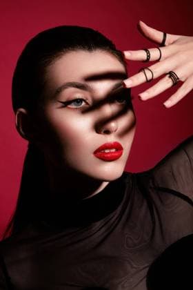  Schöne Frau in schwarzer Kleidung, klassischem Makeup und roten Lippen posiert im Studio auf einem roten Hintergrund. Schönheit Gesicht *** Beauty Woman in Schwarzer Clothing, classic Makeup and Red Lips poses at Studio at a Red Background Beauty Face Copyright: imageBROKER/NikitaxKobrin ibxnko09044858.jpg ,model released, Symbolfoto ,property released