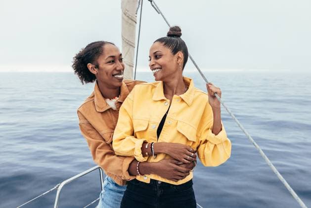 Creative Highlights Symbolbilder Cheerful African American girlfriends in casual outfits smiling and looking at each other while standing on yacht and hugging against rippling sea, Model released AlfonsoSaenz_ID12778_387439_025 Copyright: xAlfonsoxSaenzx MR