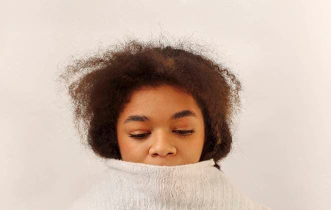 Young sad african american curly woman covering mouth with knitted sweater on beige background Headshot of young sad depressed african american curly girl isolated over beige background. Upset black female covering mouth with knitted sweater and looking down, close up. Sadness and loneliness Copyright: xZoonar.com DashaxPetrenkox 18226669 ,model released, Symbolfoto ,property released