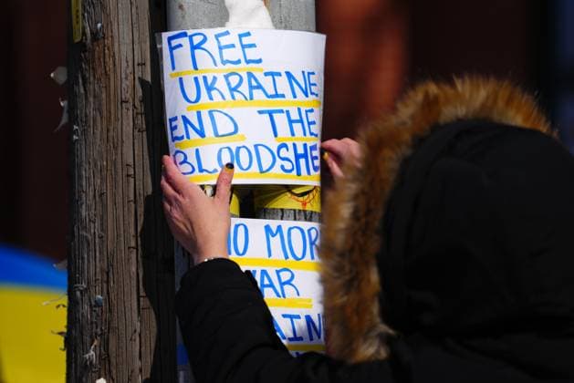 February 24, 2023, Ottawa, Ontario, Canada: A person tapes a poster to a pole as people demonstrate against the war in the Ukraine in front of the Russian embassy in Ottawa on Friday, Feb. 24, 2023. Ottawa Canada  - ZUMAc35_ 20230224_zaf_c35_022 Copyright: xSeanxKilpatrickx