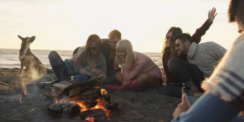 RECORD DATE NOT STATED Group of friends with dog relaxing around bonfire on the beach at sunset; Gruppe des Freunde mit Hund entspannend rund Freudenfeuer am der Strand im Sonnenuntergang ING_32193_158527