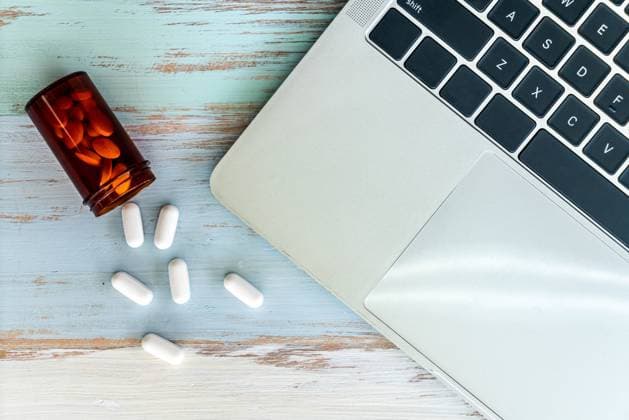 medicine spilling out laptop top view Pills medicine spilling out of pill bottle with laptop computer notebook on vintage wooden background Copyright: xZoonar.com VichayaxKiatying-Angsuleex 14458468