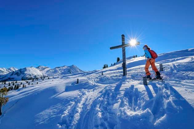 Austria, Tyrol, Female skier passing Christian cross in Zillertal Alps model released, Symbolfoto, ANSF00227