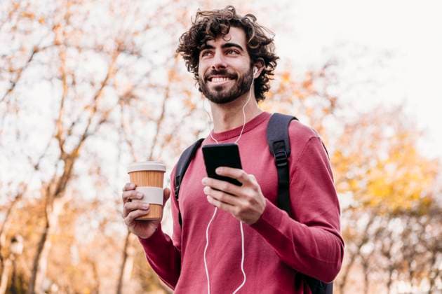 Smiling man with mobile phone and coffee cup standing at footpath model released, Symbolfoto, EBBF07868