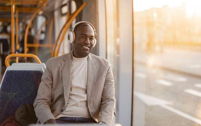 IMAGO Creative, Urban Lifestyle Smiling businessman listening to music on headphones in cable car model released, Symbolfoto, JCCMF09275