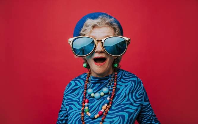 Surprised senior woman wearing big sunglasses against red background model released, Symbolfoto, OIPF02992