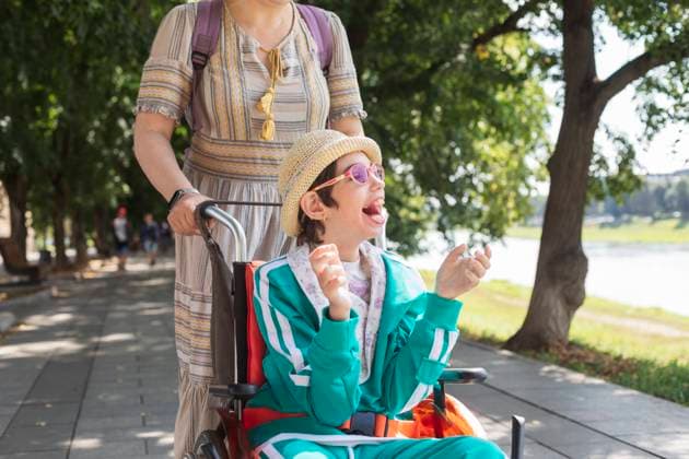 Girl with disability sitting in wheelchair and enjoying with mother on footpath model released, Symbolfoto, OSF01369