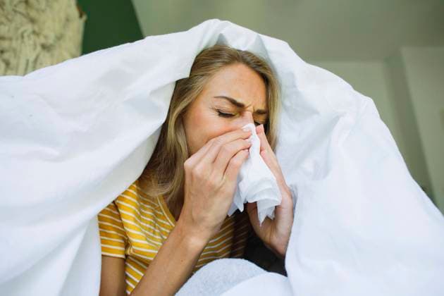 Woman wiping nose with tissue under blanket at home model released, Symbolfoto property released, TYF00729