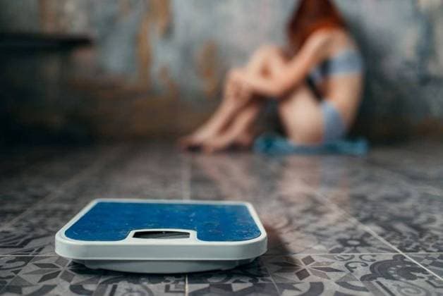 IMAGO Creative: Gesundheit, Magersucht, Bulimie RECORD DATE NOT STATED Anorexic sick woman sitting on the floor, weight loss, anorexia. Fat or calories burning concept, medical illness