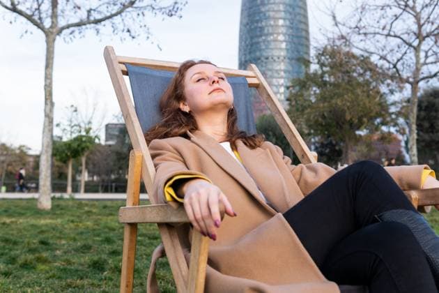 Calm female with closed eyes in warm coat napping in chaise lounger while chilling in park on weekend in autumn DavidMunoz_ID12967_394485_010 Copyright: xDavidxMunozx Model Released