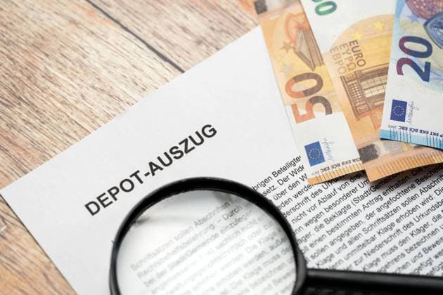25 February 2023: Magnifying glass with euro gel bills over document with heading: Deposit statement *** Lupe mit Euro Gelscheinen über ein Dokument mit Überschrift: Depot Auszug