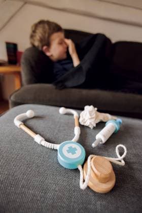Symbolfoto zum Thema krankes Kind: Ein fuenfjaehriger Junge liegt zu Hause auf einer Couch hinter einem Stethoskop, einer Spritze und einem Taschentuch. Berlin, 14.03.2023 Berlin Deutschland *** Sick child symbol photo A five-year-old boy lies on a couch at home behind a stethoscope, a syringe and a handkerchief Berlin, 14 03 2023 Berlin Germany Copyright: xThomasxTrutschel photothek.dex