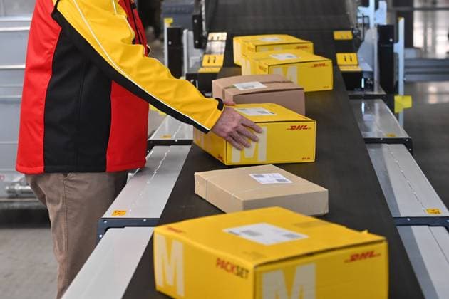 Deutsche Post DHL nimmt groessten Paket Standort Deutschlands am 20.03.2023 in Betrieb. Bearbeituing von bis zu 72000 Pakete pro Stunde im Paketzentrum Aschheim II bei Muenchen. Arbeiter legt Pakete auf ein Band,Transportband. *** Deutsche Post DHL starts operation of Germanys largest parcel facility on 20 03 2023 Processing of up to 72000 parcels per hour at the Aschheim II parcel center near Munich Workers place parcels on a belt, conveyor belt