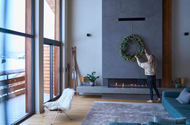 Woman adjusting Christmas wreath in living room at chalet model released, Symbolfoto property released, JAHF00182