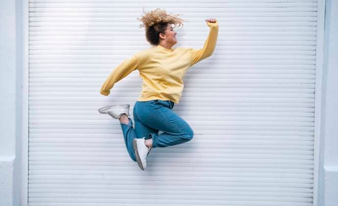 Creative Highlights Symbolbilder Carefree young woman jumping by closed white shutter model released, Symbolfoto, AMWF01190