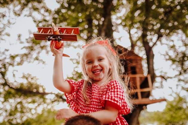 Creative Highlights Symbolbilder Happy girl holding wooden toy airplane model released, Symbolfoto, MDOF00814