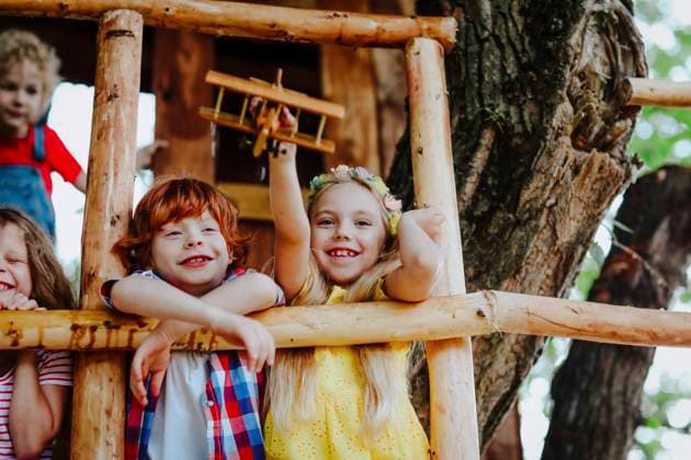 IMAGO Creative, Leben im Bamhaus Smiling girl playing with toy airplane by friends on tree house model released, Symbolfoto, MDOF00815