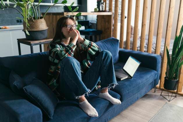 Depressed young woman sitting on sofa at home model released, Symbolfoto property released, ANNF00073