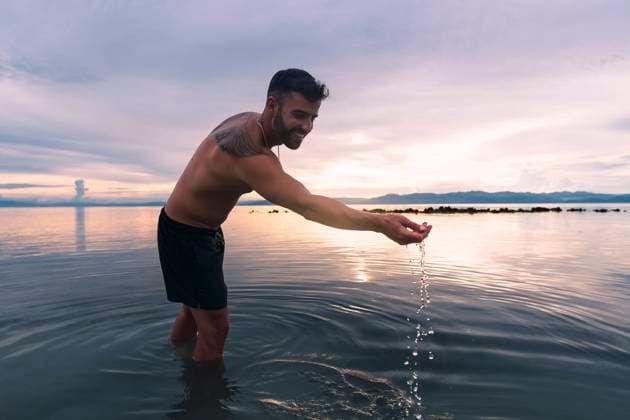 Happy man playing with water and enjoying sunset at beach model released, Symbolfoto property released, PNAF05019