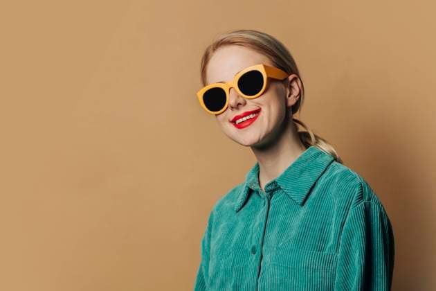 Happy woman wearing sunglasses standing against brown background model released, Symbolfoto, VSNF00544