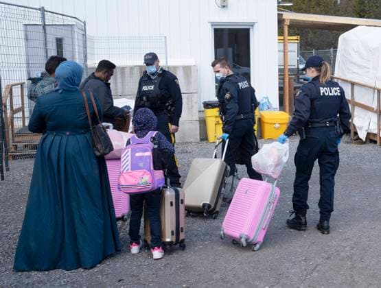 March 24, 2023, Champlain, New York, United States: RCMP officers help a family of asylum seekers with their luggage as they cross the border at Roxham Road from New York into Canada on Friday, March 24, 2023 in Champlain, N.Y. Champlain United States  - ZUMAc35_ 20230324_zaf_c35_127 Copyright: xRyanxRemiorzx