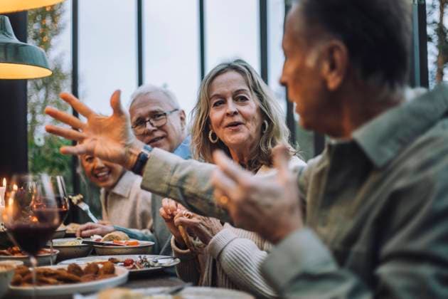 Senior woman listening to male friend gesturing while talking at dinner party Sweden, Stockholm, model released, property released Copyright: xMaskotx , MA100231 MA100231