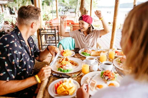 Happy girl clenching fists while parents having breakfast at table in resort Thailand, Ko Lanta, model released, property released Copyright: xMaskotx , MA100499 MA100499