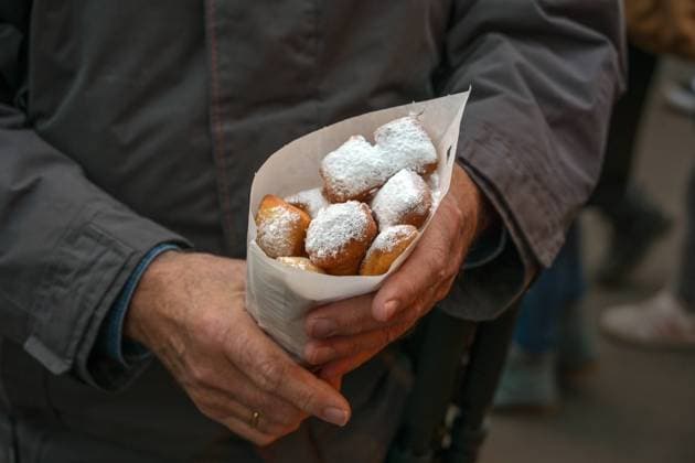 Man holding a paper bag of Mutzenmandeln, deep fried shortcrust dough pastry with almonds covered with powdered sugar, traditional German fair snack on Christmas, New Year and Carnival, copy space Man holding a paper bag of Mutzenmandeln, deep fried shortcrust dough pastry with almonds covered with powdered sugar, traditional German fair snack on Christmas, New Year and Carnival, copy space Copyright: xZoonar.com MARENxWINTERx 19393322