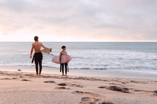 Distant male friends with surfboards and naked torso walking along wet sandy coast near waving sea and looking away during sunset, Model released NicoMortarini_ID13416_408702_012 Copyright: xNicoxMortarinix MR